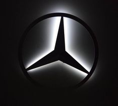 the mercedes logo is lit up in the dark with light coming through it's center