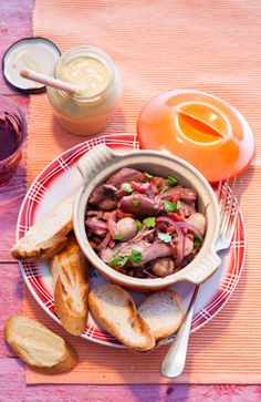 a bowl of food sitting on top of a red and white plate next to bread