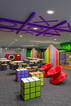 the children's play area has colorful walls and furniture, including chairs, tables, and cubes