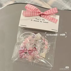 a glass table topped with lots of pink and white bracelets next to a card