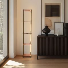 a living room with a large window and a shelf in the corner next to it