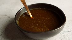 a small metal bowl filled with brown liquid and a wooden spoon in the top right corner