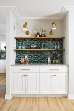 a kitchen with white cabinets and gold accents on the counter tops, along with brass pendant lights