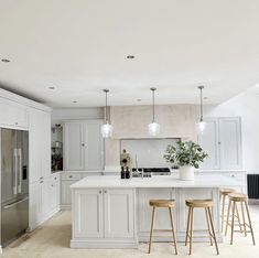 a kitchen with two stools and an island in the middle, surrounded by white cabinets