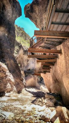 an outdoor area with rocks and stairs leading up to the top of a mountain side