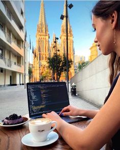 a woman sitting at a table with a laptop and cup of coffee in front of her