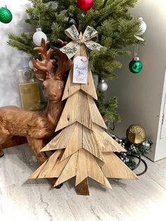 a wooden christmas tree sitting next to a fake deer and other ornaments on the floor