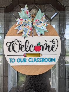 a welcome sign hanging on the front door of a school building with an apple and pencil in it