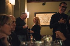 a group of people standing around a table with wine glasses