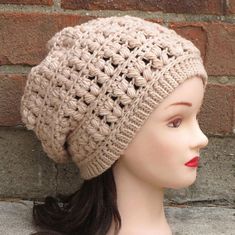 a mannequin head wearing a crochet hat on top of a brick wall