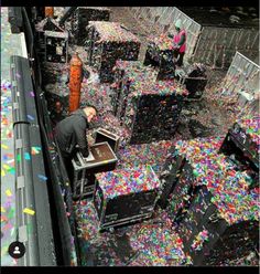 a man is standing in the middle of a room full of boxes and confetti