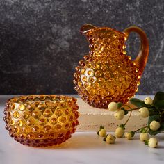 two yellow glass vases sitting on top of a white table next to each other