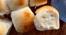 several pieces of bread sitting on top of a wooden cutting board next to a blue napkin