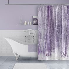 a bath tub sitting next to a shower curtain covered in purple and white watercolors