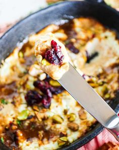 a close up of a spoon in a casserole dish with bread and cranberry sauce