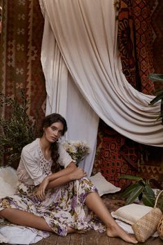 a woman is sitting on the floor in front of curtains and rugs with flowers