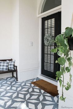 the front door is decorated with black and white geometric tiles, along with a potted plant