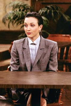 a woman sitting at a table in a suit