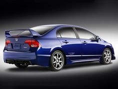 the rear end of a blue honda civic hatchback car on a black background,