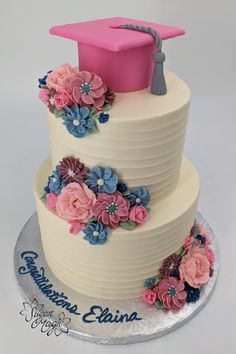 a three tiered cake decorated with flowers and a graduation cap