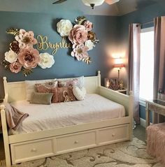 a white bed sitting in a bedroom next to a dresser and mirror with flowers on it