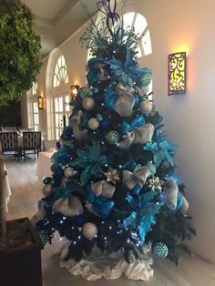 a blue christmas tree in the middle of a room with white and silver decorations on it