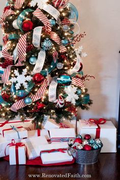 a christmas tree with presents under it and ribbon on the top is decorated in red, white and blue