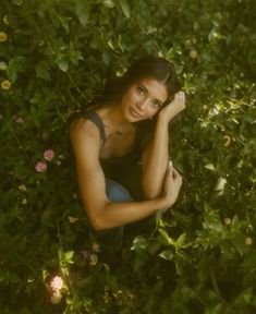 a woman is posing in the middle of some flowers