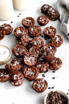 chocolate cookies with powdered sugar on top and two cups of milk next to them