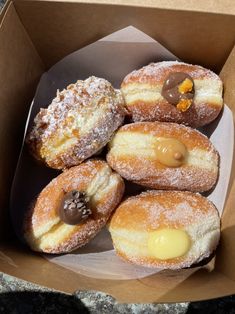 a cardboard box filled with donuts covered in powdered sugar and chocolate toppings