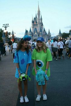 two girls dressed in costumes standing next to each other at a disney world event with the castle in the background