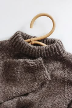 a brown sweater with a wooden hanger attached to it's collar and back