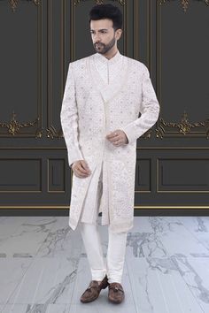 This two-layer sherwani features intricate stones and zardozi, making it perfect for a stylish groom. Step up your traditional attire game with this unique and elegant piece. Eid Traditional Wear With Stone Work, Formal Festive Sets With Stone Work, Traditional Long Nehru Jacket With Naqshi, Ceremonial Long Sherwani With Dabka, Ceremonial Long Sherwani With Resham Embroidery, Traditional Formal Sets With Stone Work, Elegant Sherwani With Dabka Work And Traditional Drape, Ceremonial Long Sherwani With Naqshi, Elegant Traditional Wear With Stone Work For Designer Occasions