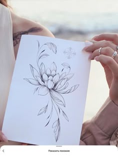 a woman holding up a piece of paper with a drawing on it's side