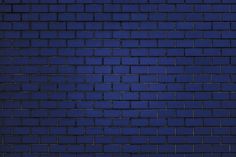 a dark blue brick wall with some light shining on the top and bottom part in the middle