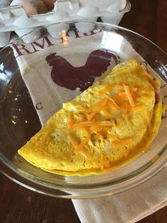 an omelet in a glass bowl with cheese on top and a napkin next to it