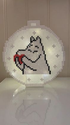 a white plastic object with a red bow on it's head, sitting on top of a table