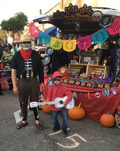 two people in costumes are standing near a table with decorations on it and one person is holding a guitar