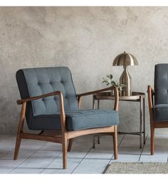 two chairs sitting next to each other in front of a table with a lamp on it