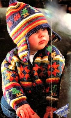 a young child wearing a colorful knitted jacket and hat