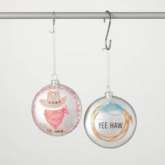 two christmas ornaments hanging from a clothes line with the words yee haw on them