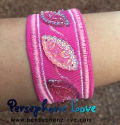 a close up of a person's arm wearing a pink bracelet with beads and sequins