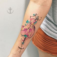 a woman's arm with watercolor tattoos on it and an arrow in the shape of a dress