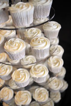 cupcakes with white frosting sitting on a cake stand