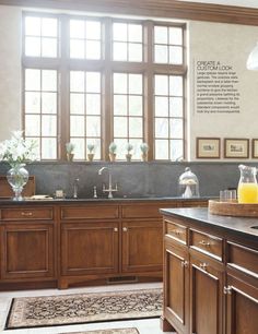 a large kitchen with wooden cabinets and black counter tops, along with an area rug on the floor