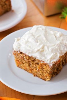 a piece of carrot cake with frosting on a plate next to some carrots