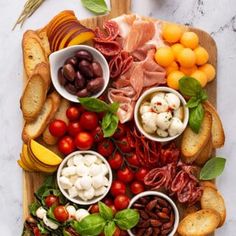 a wooden platter filled with different types of meats, cheeses and vegetables