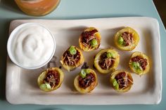 small appetizers are arranged on a plate with a cup of yogurt