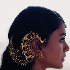 a close up of a woman wearing gold ear rings and earrings with pearls on them