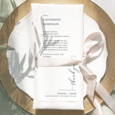 the wedding stationery is laid out on top of a plate with a ribbon tied around it